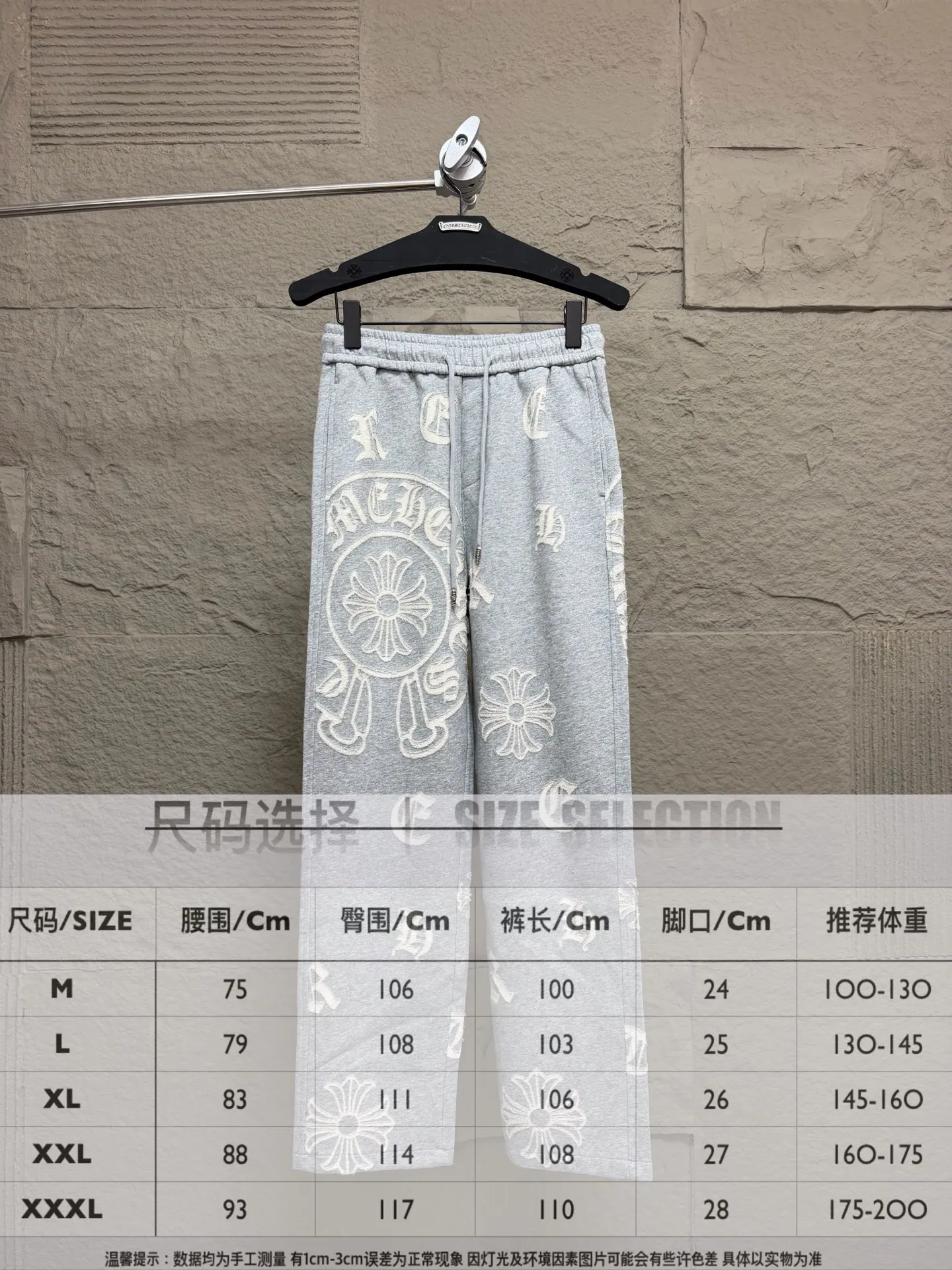 CH/Cro Heart 2026ss Burnt Flower Straight-leg Sweatpants Classic heavy-weight sweatpants with gray tones, Retro street style full-fitting, direct recognition, same style for men and women. ●Three-dimensional patchwork technology: The whole body is covered with Gothic letters + cross flower totems, using raw edge patchwork embroidery, with a mustache-like old texture, and uneven and layered patterns. It is not an ordinary print, and it is durable and not easy to fall off. ●Style tailoring: Loose, straight and wide-legged version, modifying the shape of the legs, hiding the flesh neatly, not flattering the figure, with an online drape, and the upper body has a relaxed street tone. ●Fabric and waist: Heavy knitted terry fabric, thick and soft, with good drape; elastic drawstring waist, with branded metal engraved rope ends, easy to put on and take off, and strong waist adaptability. ●Detailed design: The side pockets are convenient for carrying items, and the back pocket is decorated with cross-pattern patches. The front and rear patterns echo each other. Every detail is highly recognizable to the brand. ●Wearing scenarios: Suitable for street wear, daily outings, and trendy wear. Paired with sweaters, denim jackets, and leather jackets, you can easily create an American retro cool style. ●The overall gray base is paired with Cream White patches, which are low-key yet impactful. They are both comfortable and trendy. Versatile sweatpants, a must-have for fashionistas, are also available at the counter. SIZE：M L XL XXL XXXL
